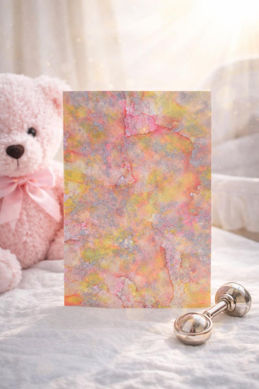 Greeting card with butterfly design, teddy bear, and baby rattle on a soft surface