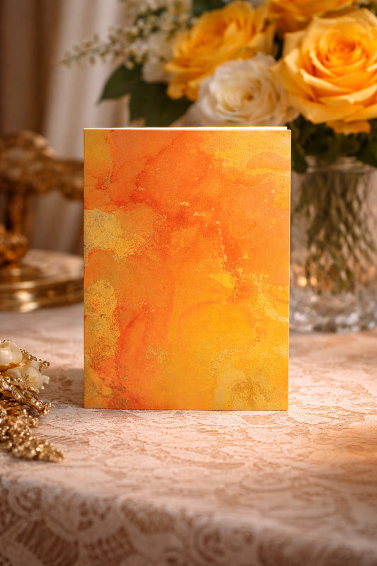 Decorative card with orange and yellow watercolor design on a lace tablecloth with flowers in the background.