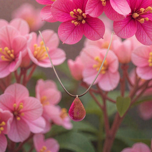 Necklace with a pink pendant in front of pink flowers