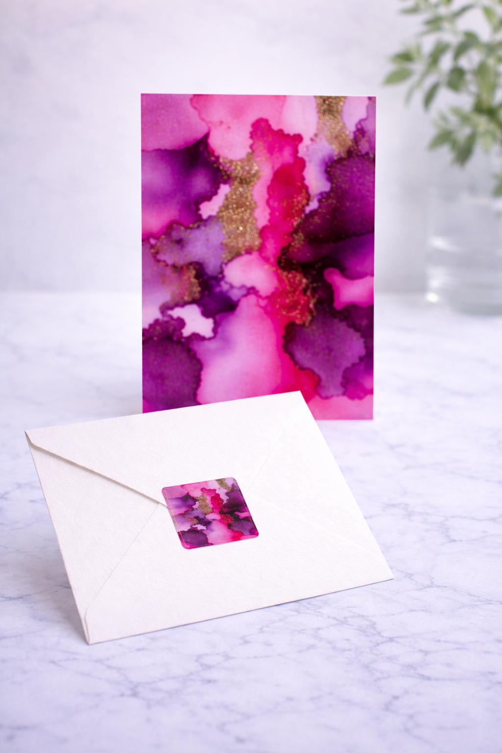 Greeting card with watercolor design and matching envelope on a marble surface.