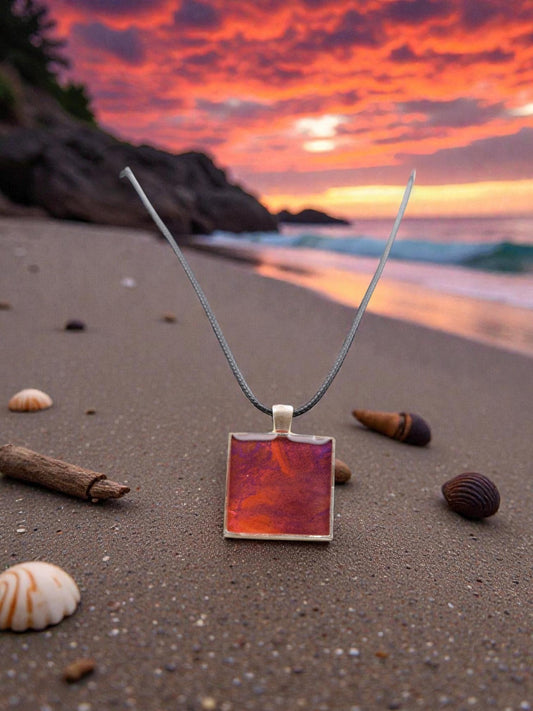 Necklace with a red pendant on a beach at sunset