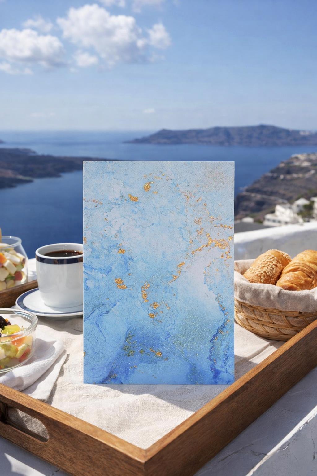 Breakfast setting on Santoirini Greece with coffee, bread, and a scenic view of the ocean and mountains.