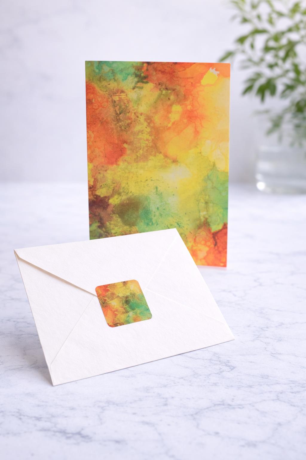 Colorful watercolor card with a matching envelope on a marble surface.
